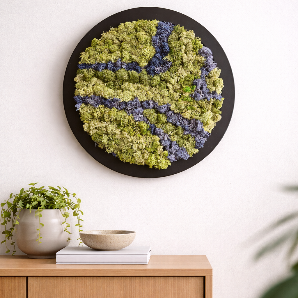 Moss wall art with a black frame on a white wall above a wooden cabinet.